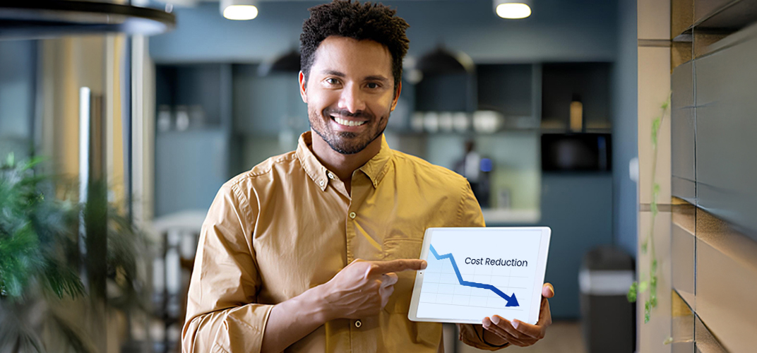 Man in a tan shirt presenting a tablet showing a downward cost-reduction chart in an office setting